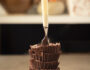 Stack of five dark chocolate sunflower butter cups on a small speckled plate, with a fork standing upright in the top cup