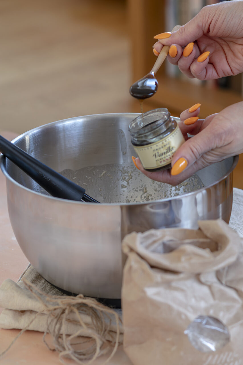 Adding vanilla paste into a mixing bowl with wet ingredients for homemade muffins.
