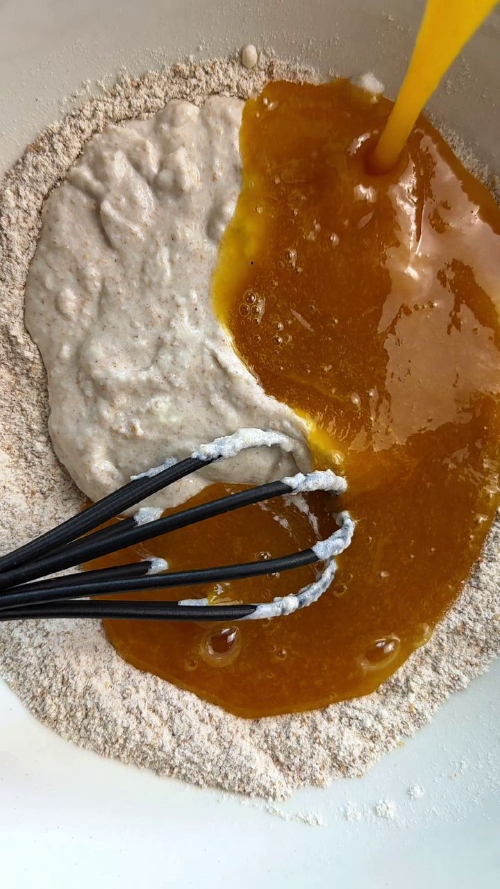 Pouring the whisked egg mixture into the flour and sourdough starter in a mixing bowl