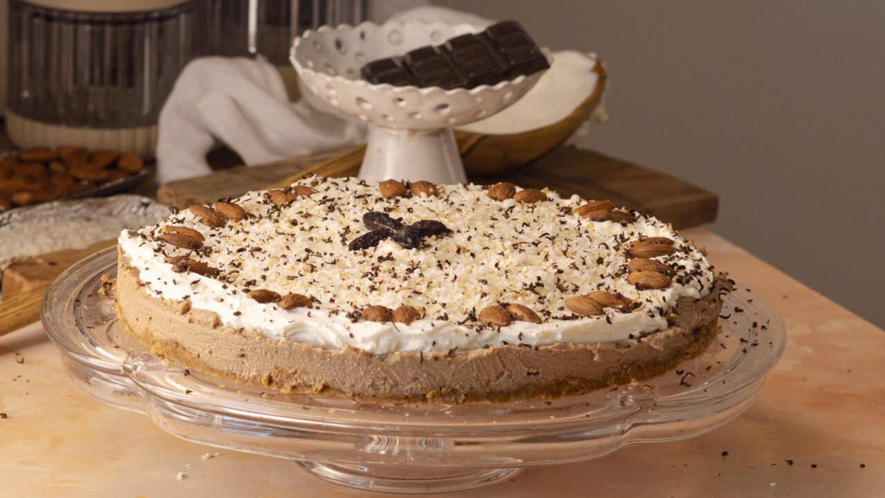 Dark, glossy no-bake coffee cheesecake with double chocolate, topped with toasted coconut and shaved chocolate